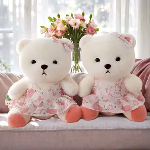 Zwei süße weiße Teddybären in rosa Blumenkleidern auf einem sehr weichen Samtsofa