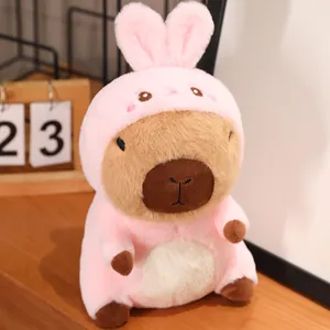 Detail view of a cute capybara plush toy wearing a pink bunny costume on a wooden shelf