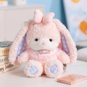 Detail shot of a soft pink long-eared bunny plush toy with a cute bib
