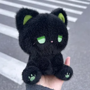 Detailansicht einer süßen schwarzen Plüschkatze mit grünen Augen in der Hand gehalten