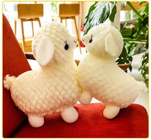 Dettaglio ravvicinato di due simpatici peluche di alpaca bianchi su una sedia rossa.