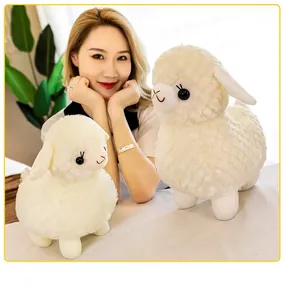 Primo piano di peluche alpaca bianchi piccoli e grandi con modella per scala di grandezza