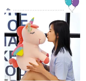 Vista detallada de un lindo peluche de unicornio rosa arcoíris sostenido por una mujer.
