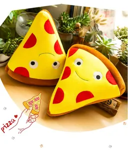 Dettaglio di due simpatici cuscini di peluche pizza su una scrivania con piante.