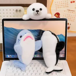 Detail shot of cute blue shark, white seal and orca marine animal plush toys on a laptop