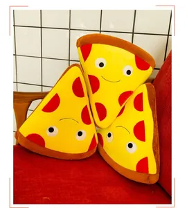 Tre simpatici cuscini di peluche a forma di pizza su un divano rosso.