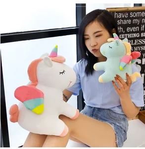 Modelo asiática sosteniendo lindos peluches de unicornio arcoíris en blanco y verde.