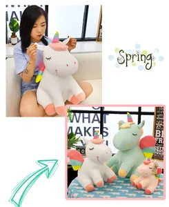 Primer plano de una modelo sosteniendo un peluche de unicornio arcoíris blanco en un hogar acogedor