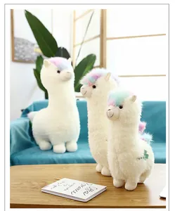 Detailed view of three white alpaca plush toys with rainbow hair in a home setting