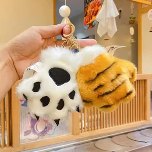 Close-up view of plush tiger and leopard paw keychains with soft faux fur texture.