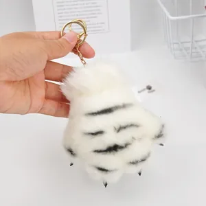 Close-up view of a soft white tiger paw plush keychain featuring realistic black stripes.