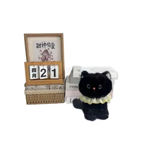 Cute black cat plush toy with yellow lace collar sitting in a cozy home setting