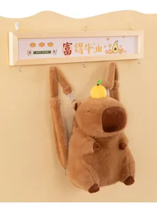 Vista dettagliata di uno zaino in peluche capibara marrone con una piccola arancia gialla.