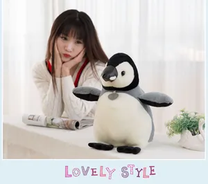 Realistic penguin plush toy shown in a warm, cozy lifestyle setting with a model.