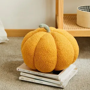 Decorative orange pumpkin plush throw pillow placed on magazines in a cozy home setting