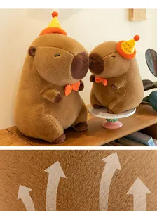 Detail view of soft breathable brown capybara plush toy with birthday hat and bowtie