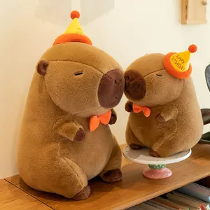 Two adorable capybara plush toys wearing festive birthday hats and orange bowties.