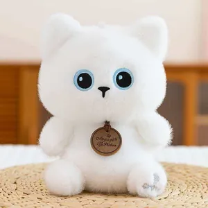 Adorable white plush doll with large blue eyes and branded wooden tag on straw mat