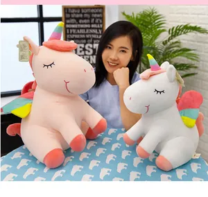 Peluches de unicornio rosa y blanco con cuernos de arcoíris en un ambiente acogedor.