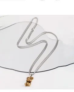 Detail view of a vintage gold bear pendant on a silver steel box chain necklace.