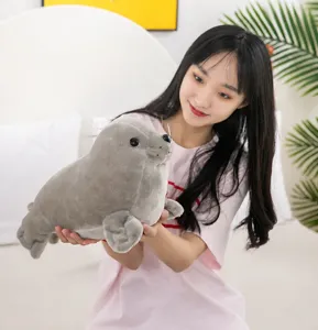 Detailed view of a realistic gray seal plush toy being held by a girl in a home setting