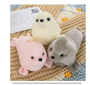 Detail of soft plush seal toys in pink, grey, and cream on a cozy knitted mat