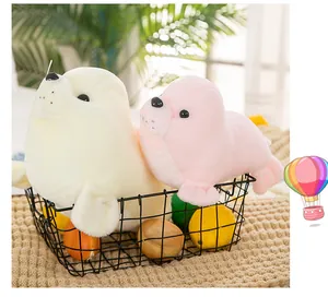Soft off-white and pink seal plush toys placed in a black wire basket detail view