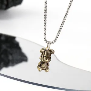 Close-up macro detail showing the textured vintage gold bear pendant on a silver box chain.