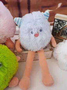 Close-up of a blue furry monster plush with long orange legs and striped horns