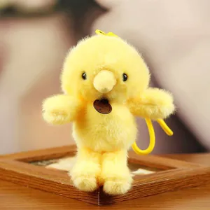 Detailed view of a fluffy yellow chick plush toy keychain on a wooden frame.