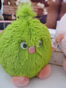 Detailed shot of a fluffy green monster plush toy with soft long fur and pink feet