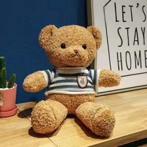 Close-up detail of a soft brown teddy bear plush toy wearing a striped blue sweater