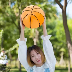 Modelo asiática sosteniendo un creativo peluche de baloncesto naranja en un parque soleado