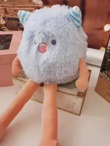 Close-up of a fluffy light blue monster plush toy with long legs and striped horns