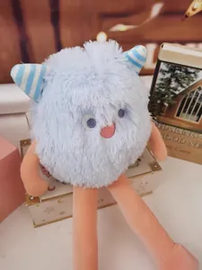 Close-up of a soft light blue long-haired monster plush toy with striped horns