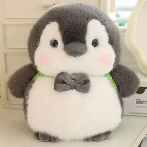 Close-up of a cute grey and white plush penguin with a bowtie and green backpack straps