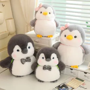 Cute penguin plush toys with backpacks and bows arranged on a cozy desk setup.