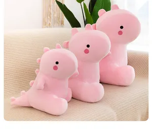 Peluches de dinosaurios rosa suaves en tres tamaños en un cómodo sofá de color beige