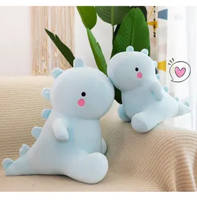 Dos lindos peluches de dinosaurio azul claro en un sofá de color crema acogedor.