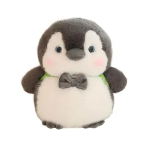 Cute truant penguin plush toy with bowtie and green backpack straps on white background