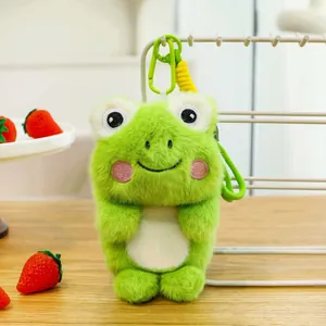 Detailed close-up of a cute green frog plush toy keychain on a bright wooden desk