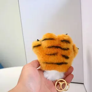 Detailed macro view of a soft 12cm orange plush tiger paw keychain with a gold ring