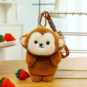 Close-up of a cute brown plush monkey keychain accessory on a wooden desk with strawberries
