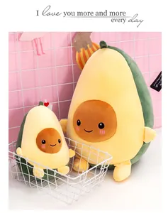 Due simpatici peluche di avocado di diverse dimensioni in un cesto su fondo rosa.