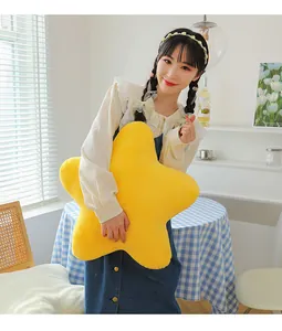 Soft yellow star plush pillow held by a model for a cozy indoor home decoration