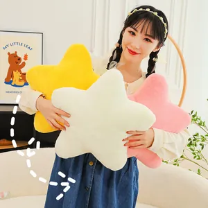 Soft Nordic star-shaped plush pillows in yellow, white, and pink held by a model