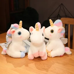 Drei niedliche weiße Einhorn-Plüschtiere mit bunten Mähnen auf einem Holztisch.
