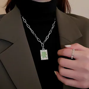 Close-up of Mahjong 'Fa' character pendant necklace with sparkling green crystals.