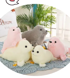 Realistic seal plush toys in multiple colors like pink and cream displayed on a cozy blue rug.