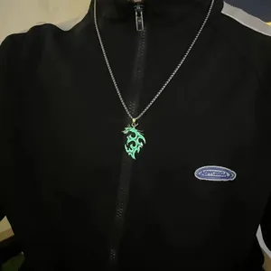 Primo piano della collana con ciondolo a forma di drago verde brillante su tuta nera
